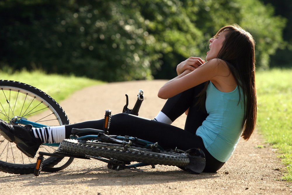 A young woman grasping at her knee after a fall.