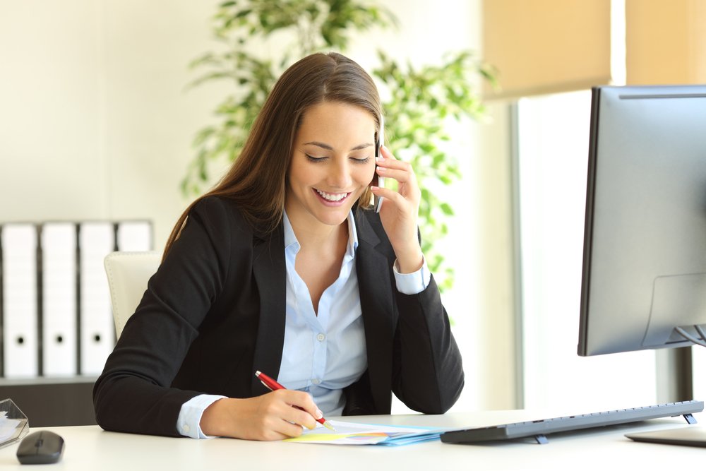 Recepcionista sonriendo mientras contesta una llamada.