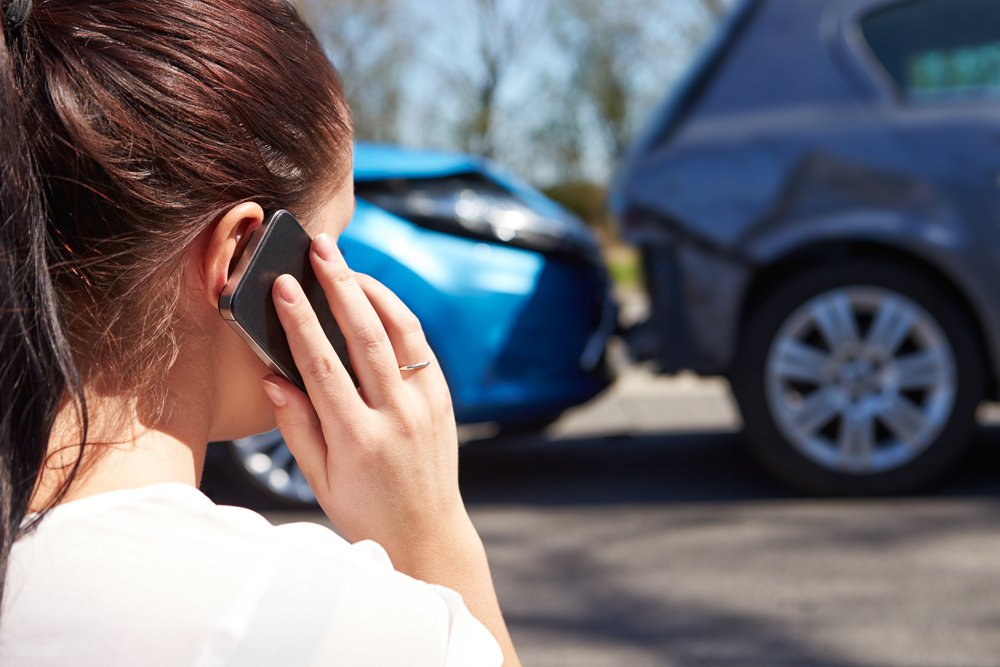 Woman calling insurance company after fender bender accident where both drivers were at fault