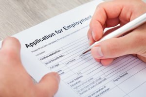 Hand filling out an employment application without a question regarding criminal history