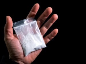 Hand holding baggie of ketamine ready to be sold in violation of NRS 453.338