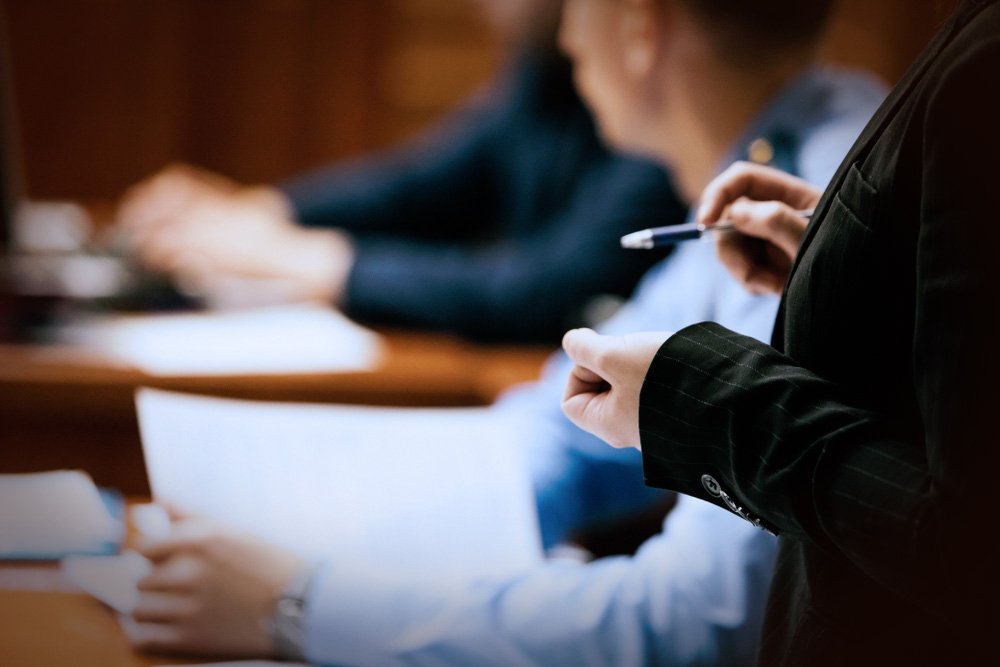 Un abogado de pie en la mesa de abogados y dirigiéndose a la corte durante un juicio por jurado