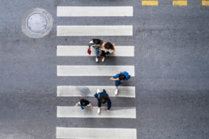 Overhead view of four pedestrians crossing a marked crosswalk.