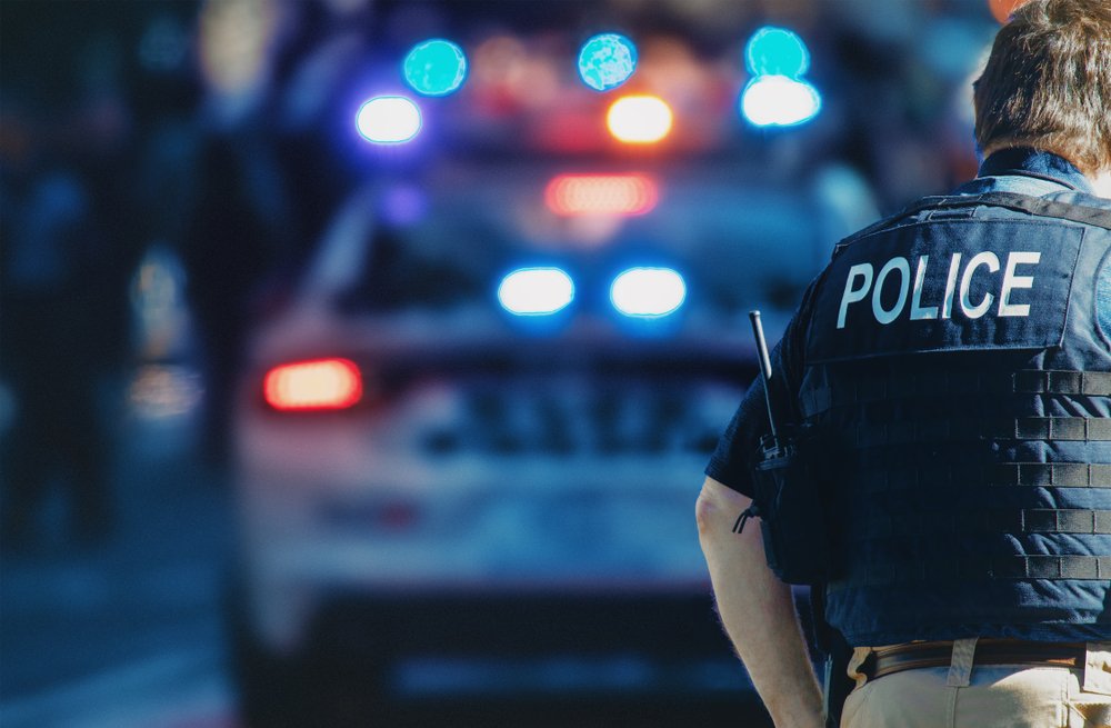 Oficial de policía junto a un vehículo policial.