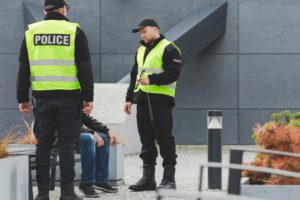 Police serving a warrant to a man sitting on a bench.