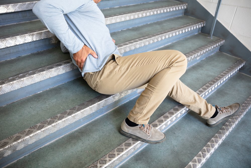 Hombre sosteniendo su espalda después de una lesión en las escaleras.