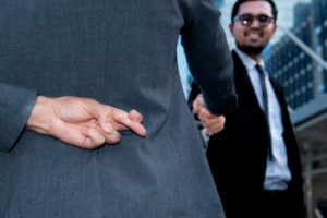 Un no abogado estrechando la mano de un cliente mientras cruza los dedos detrás de su espalda, indicando que está ejerciendo la práctica no autorizada de la abogacía en violación del BPC 6126 en California