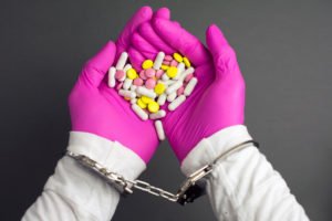 Las manos de los médicos con guantes en esposas sosteniendo medicamentos recetados obtenidos ilegalmente en violación de la NRS 453.421