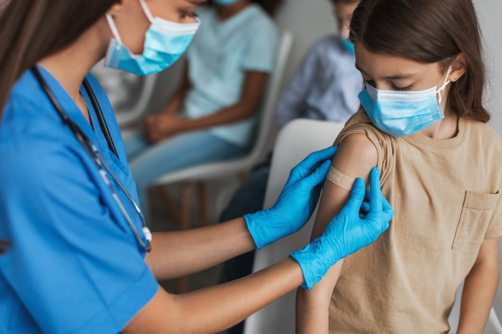 Una enfermera aplicando una venda en el brazo de un niño joven.