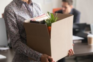 Ex-empleado llevando caja de pertenencias de oficina después del despido según lo definido por el Código de Trabajo 1400.5