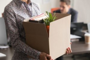 Laid off worker carrying box of belongings out of office