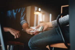 Hombre entregando dinero a otro por aceptar ocultar un delito en violación de PC 153