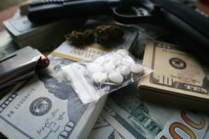 Una pistola, una bolsa de drogas y dinero para representar una violación de NRS 207.400.