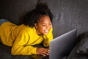 A teen smiling while on her laptop.