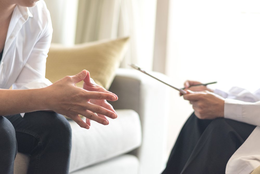 Closeup of a dentist receiving counseling from a therapist in a room where they are both sitting on couches