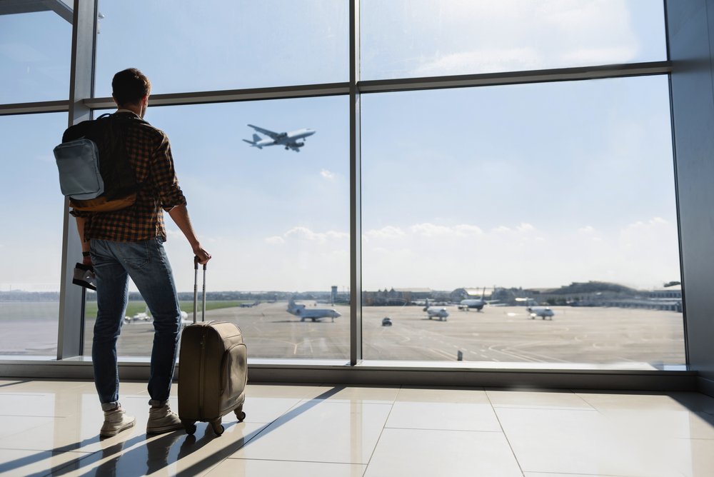 A young man watching airplanes from the terminal.