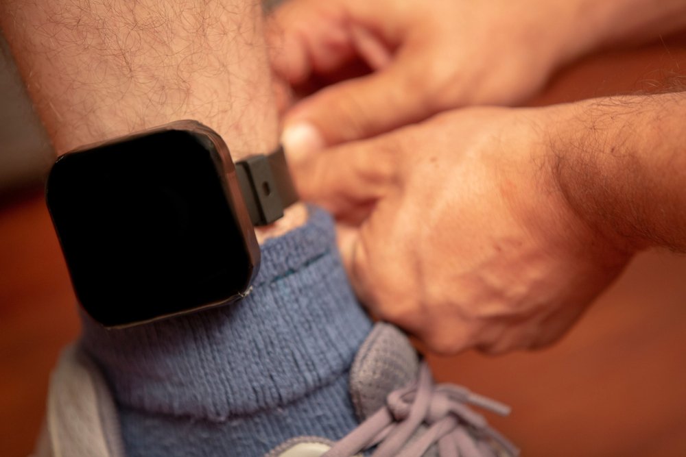 An ankle monitor being put on a man's ankle.