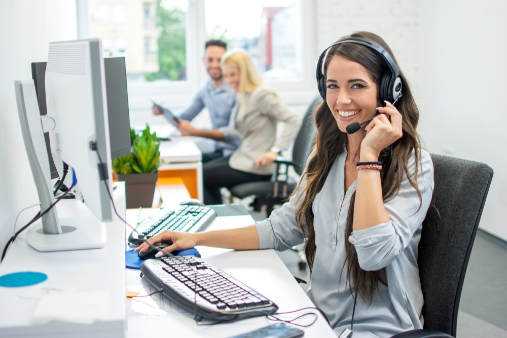 Recepcionista sonriente al teléfono.