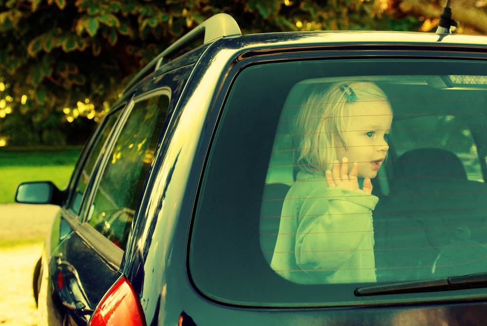 A child left alone in a car with rolled up windows.