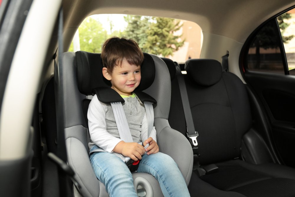 Niño lindo en el asiento trasero de un automóvil.
