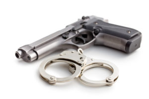 Gun and handcuffs against white background