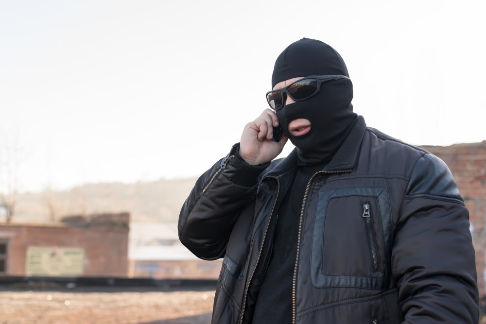 A masked ruffian receiving orders over the phone.