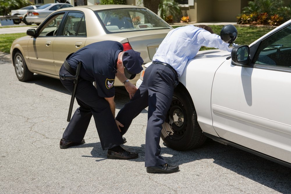 Un oficial de policía palmeando a un sospechoso - la policía tiene poder limitado para realizar registros de alto y detención en California