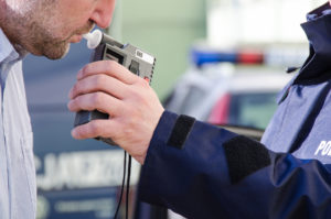 Un conductor soplando en un alcoholemetro de carretera después de una parada de tráfico por DUI