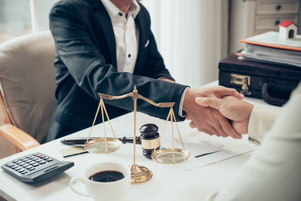 An attorney shaking hands with his client, possibly because he was able to drop the DUI charges down to reckless driving.