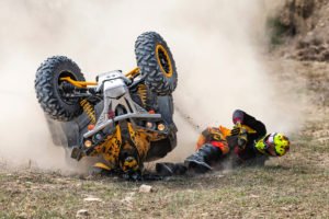 Vehículo ATV volcado con conductor en el suelo