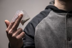 Man holding a small baggie of cocaine he just bought from a dealer