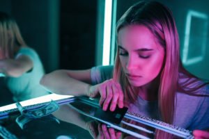 Woman forming a line of cocaine on a glass table with some cash nearby