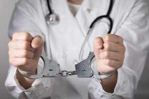 Doctor in white coat with hands in cuffs following a 2052 BPC arrest