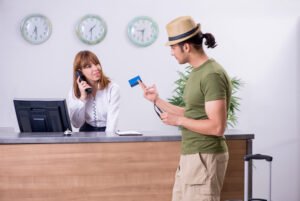 Tourist holding credit card out to hotel clerk