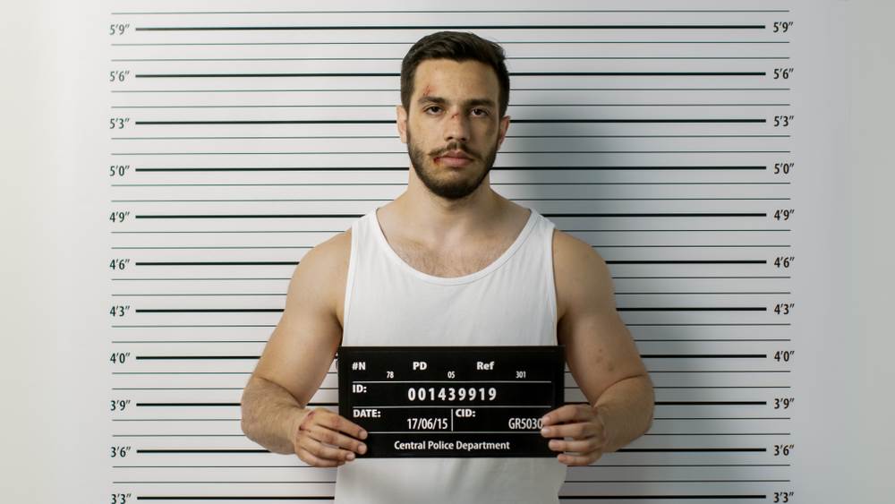 A mugshot of a man holding up a name placard.
