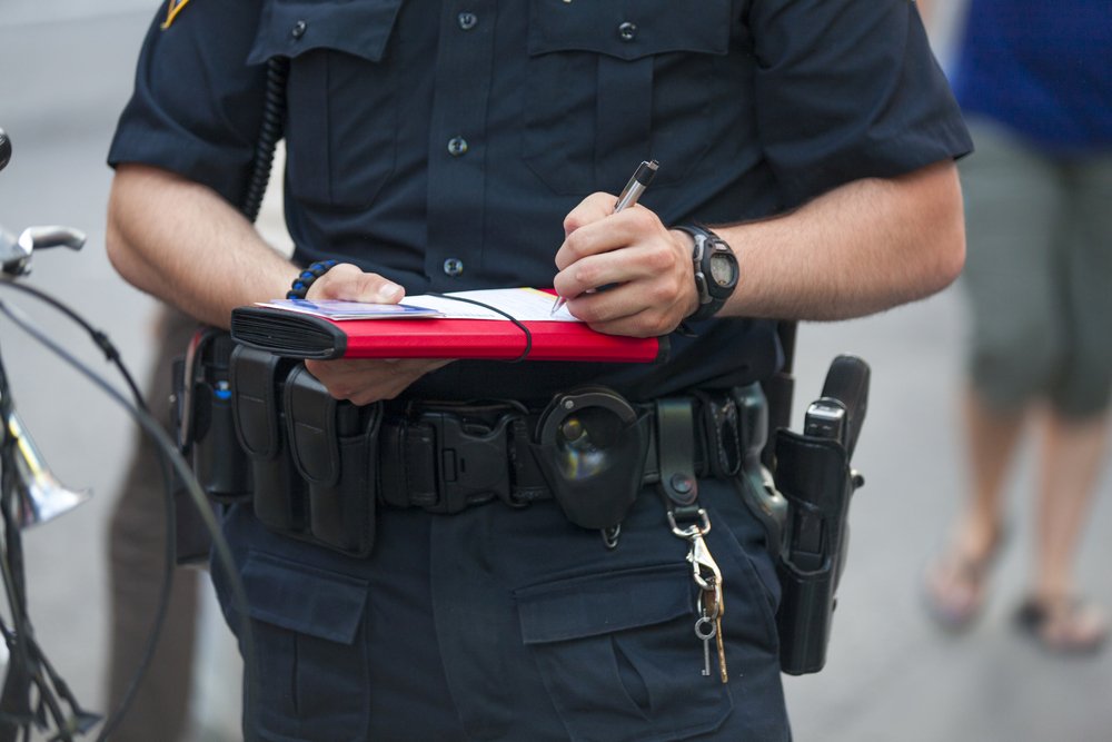 A police officer writing a ticket, possibly in regards to illegal fireworks.