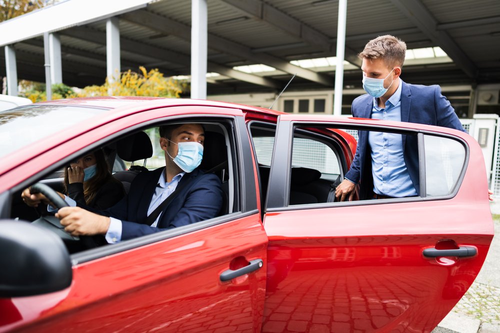 A passenger climbing into the rear seat of a ride share car.