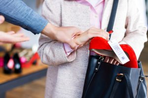 Mujer cometiendo robo menor en violación del 490.2 PC al poner una camisa en su bolso en una tienda