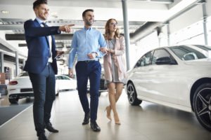 A car salesman showing an excited couple a new car.