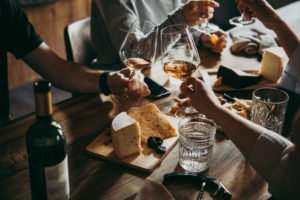 A group toasting with wine over a table filled with food.