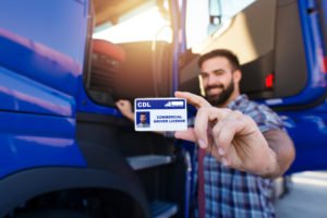 A truck driver holding up his license.