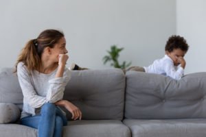 Parent sitting on couch looking at misbehaving child