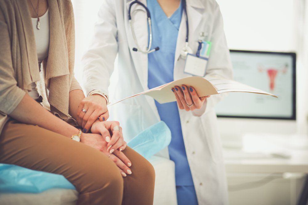 A doctor standing next to her patient.