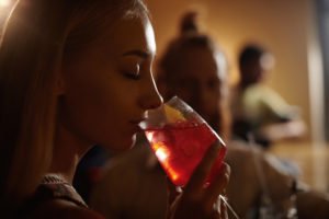 A girl taking a drink while a man watches on.