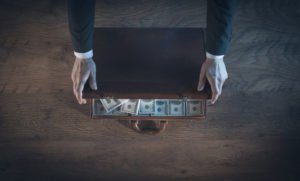 A man opening a briefcase filled with cash.