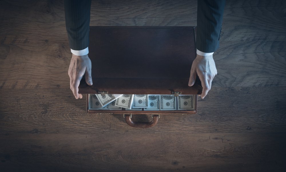 A man opening a briefcase filled with cash.