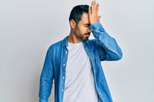 A man gesturing at his head in annoyance, possibly in response to forgetting something.