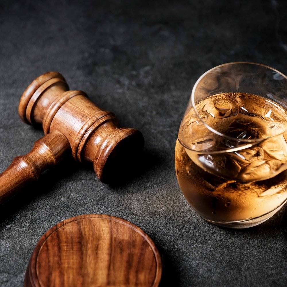 A judge's gavel next to a glass of whiskey.