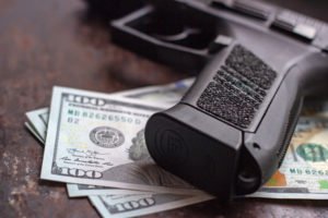 A gun resting on a few hundred dollar bills.