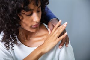 A woman brushing off the hand of a man off her shoulder.